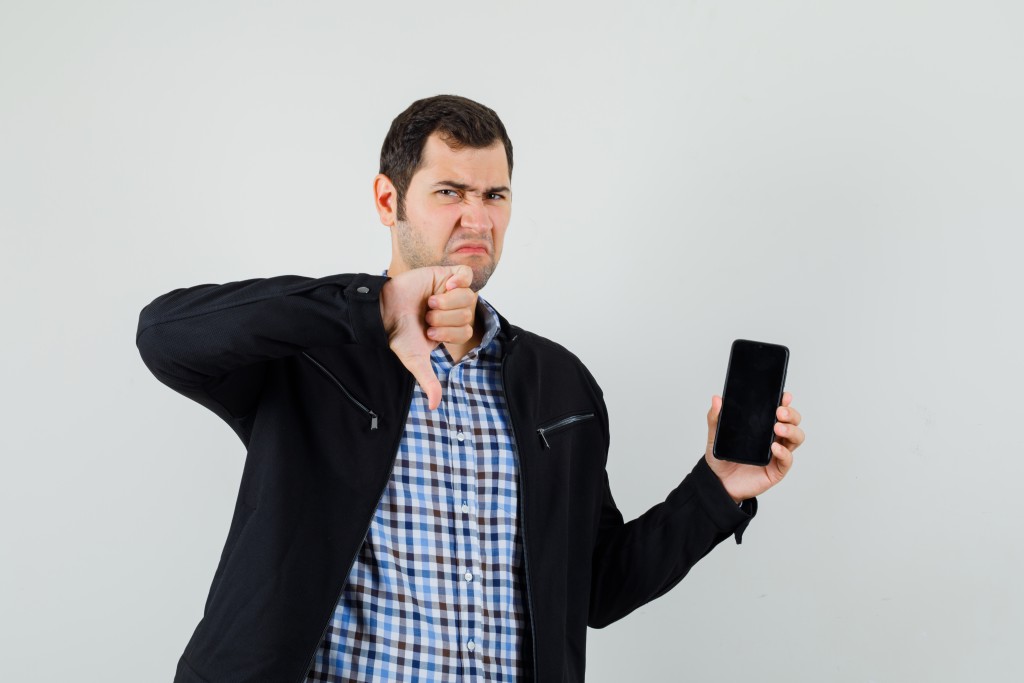 molodoi-celovek-derzit-mobil-nyi-telefon-pokazyvaet-palec-vniz-v-rubaske-kurtke-i-vygladit-mracno.jpg molodoi-celovek-derzit-mobil-nyi-telefon-pokazyvaet-palec-vniz-v-rubaske-kurtke-i-vygladit-mracno.jpg